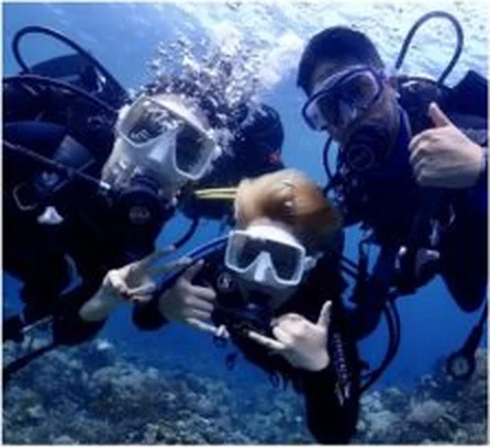 Three smiling divers underwater giving the OK sign